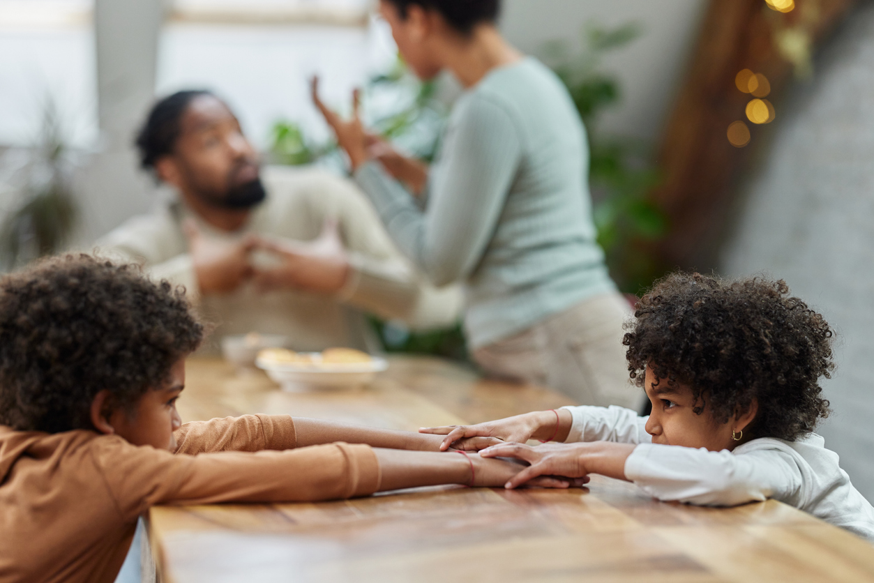 Displeased black kids holding hands while their parents are arguing. Co-Parenting Strategies That Reduce Conflict—and Why It Matters for Kids